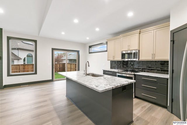 kitchen featuring light hardwood / wood-style floors, appliances with stainless steel finishes, sink, and an island with sink