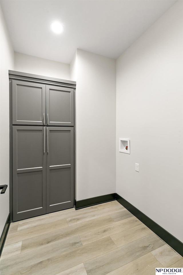 laundry area with light hardwood / wood-style floors, washer hookup, and cabinets