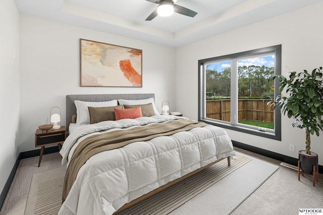 bedroom with carpet flooring, ceiling fan, and a raised ceiling