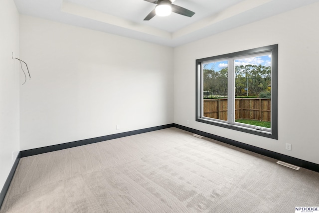 spare room featuring ceiling fan, a raised ceiling, and carpet