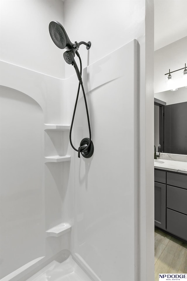 room details featuring a shower, hardwood / wood-style flooring, and vanity