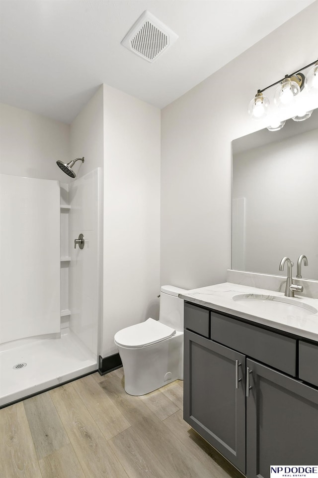 bathroom with walk in shower, wood-type flooring, vanity, and toilet