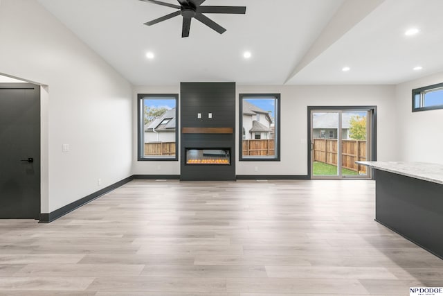 unfurnished living room featuring a fireplace, ceiling fan, light hardwood / wood-style flooring, and lofted ceiling