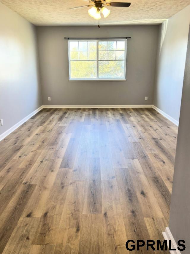 empty room with hardwood / wood-style flooring, ceiling fan, and a textured ceiling