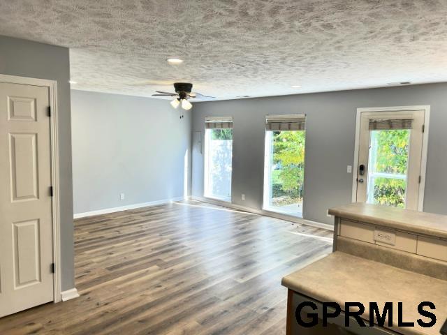 unfurnished living room with hardwood / wood-style flooring, ceiling fan, and a textured ceiling