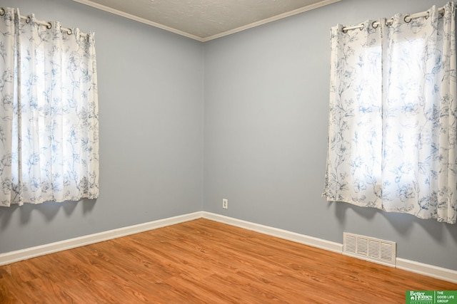 spare room featuring a textured ceiling, wood-type flooring, and crown molding