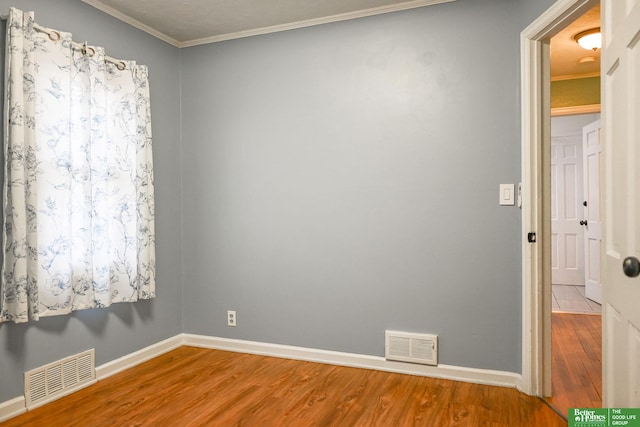 empty room featuring hardwood / wood-style flooring and crown molding