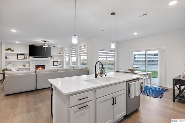 kitchen featuring light hardwood / wood-style floors, white cabinets, dishwasher, sink, and an island with sink