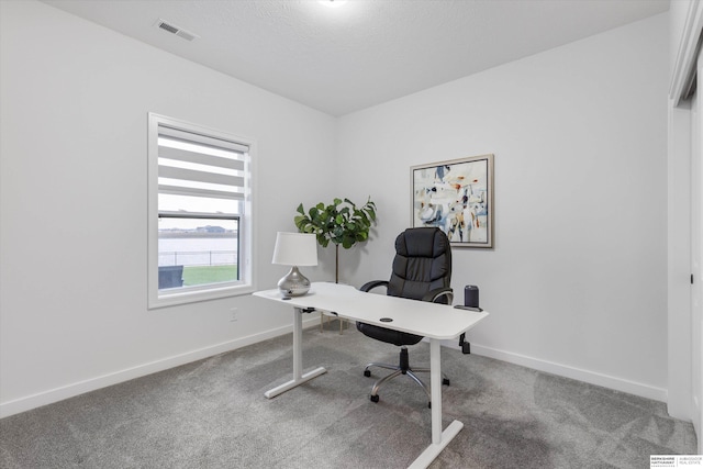 carpeted home office featuring a textured ceiling