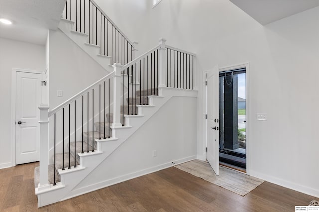 entryway with hardwood / wood-style flooring and a towering ceiling