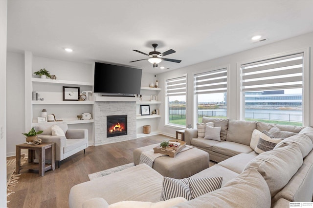 living room with a fireplace, built in features, hardwood / wood-style flooring, and ceiling fan