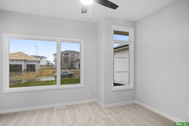 spare room featuring light carpet and ceiling fan