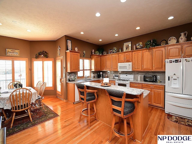 kitchen featuring a wealth of natural light, a center island, white appliances, and sink