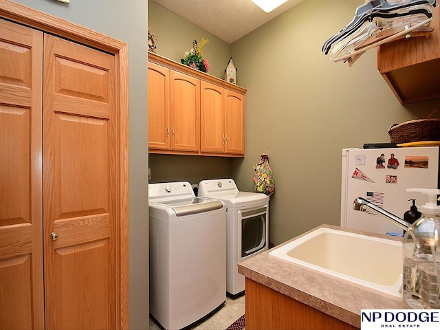 washroom with cabinets, washer and dryer, a textured ceiling, and sink