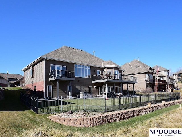 rear view of property featuring a yard, a balcony, and a deck