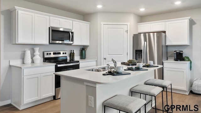 13521 Whitmore St, Omaha, NE 68142 - kitchen with appliances with stainless steel finishes, an island with sink, white cabinetry, light wood-style floors, and a breakfast bar area