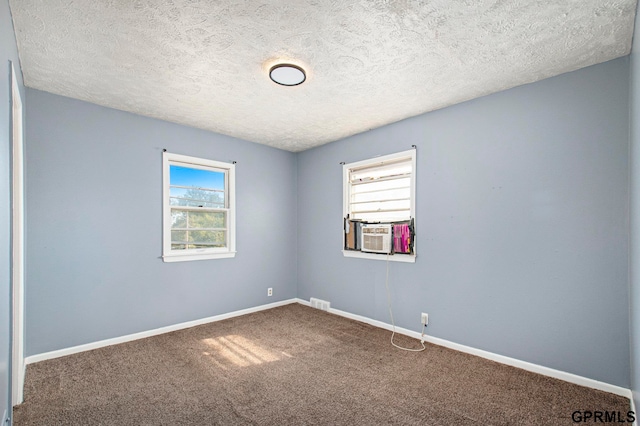 carpeted empty room featuring cooling unit and a textured ceiling