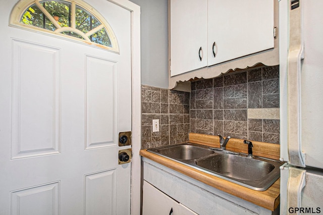 kitchen with white cabinetry, decorative backsplash, sink, and white refrigerator