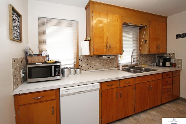 kitchen featuring a wealth of natural light, tasteful backsplash, sink, and white dishwasher