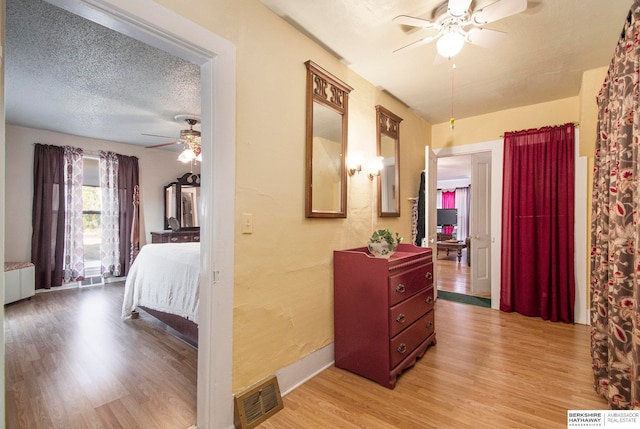 bedroom featuring radiator heating unit, ceiling fan, light wood-type flooring, and a textured ceiling