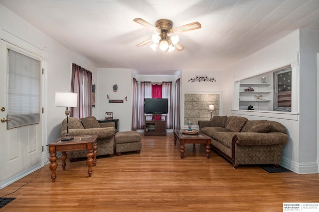 living room with ceiling fan, light wood-type flooring, and built in features