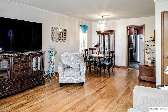 living room featuring ornamental molding, an inviting chandelier, and light hardwood / wood-style floors