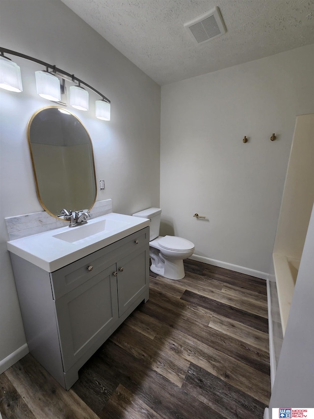 bathroom with hardwood / wood-style floors, a textured ceiling, toilet, and vanity