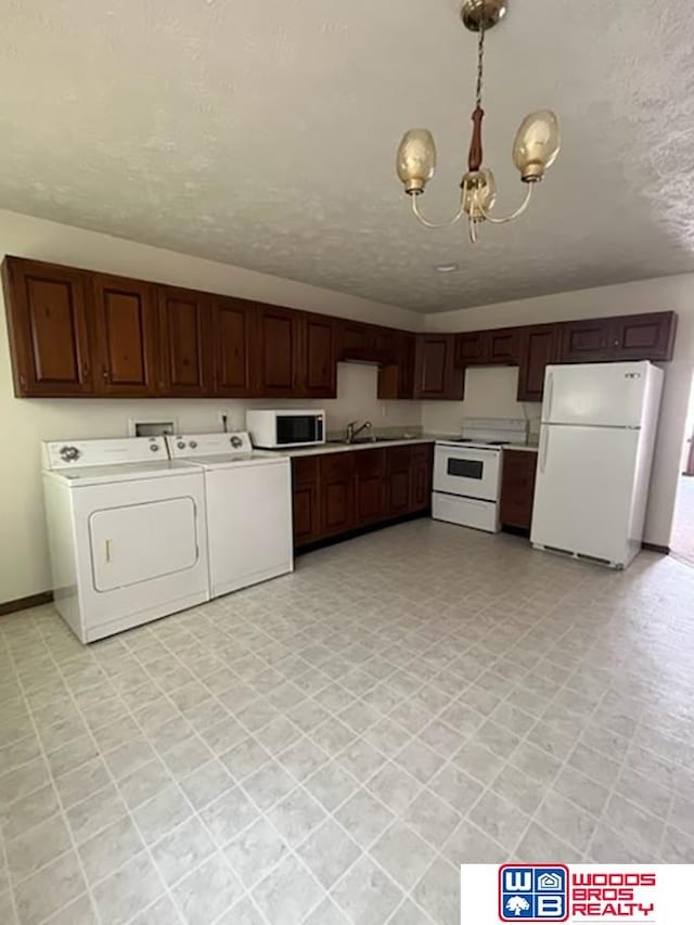 kitchen featuring a textured ceiling, white appliances, a chandelier, washing machine and clothes dryer, and pendant lighting