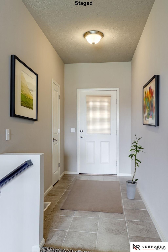 doorway featuring a textured ceiling and light tile patterned floors