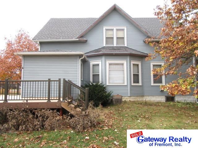 back of house with a deck and a lawn