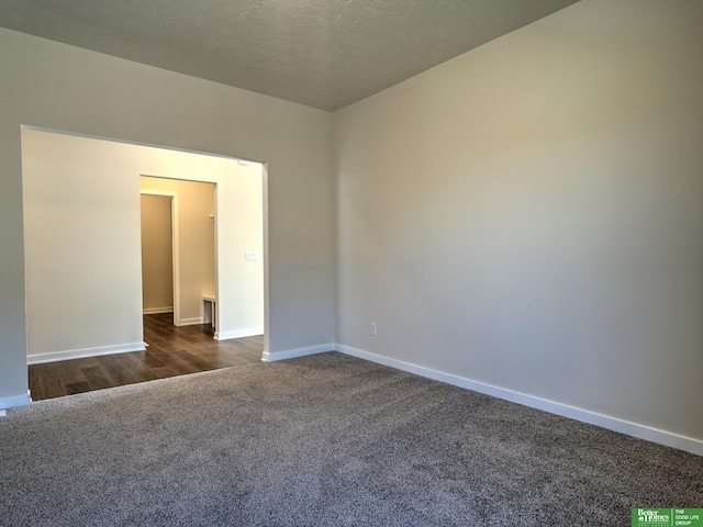 unfurnished room with a textured ceiling and dark hardwood / wood-style floors