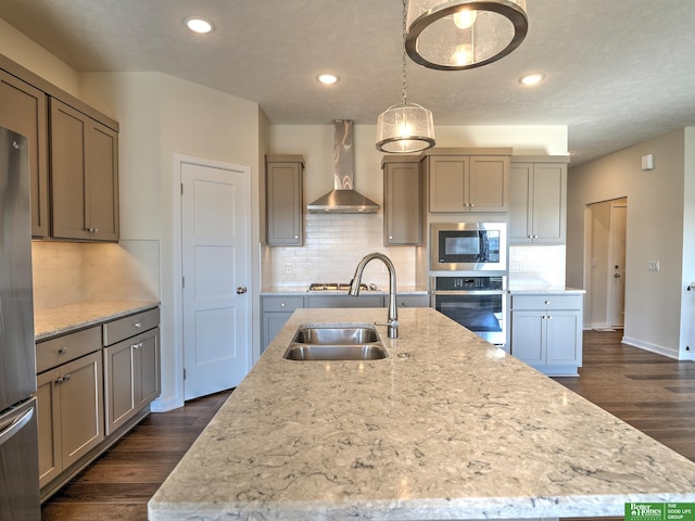 kitchen with stainless steel appliances, dark hardwood / wood-style flooring, sink, an island with sink, and wall chimney exhaust hood