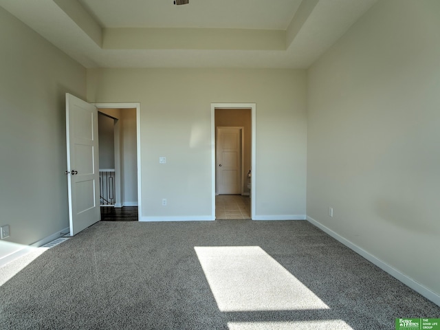 unfurnished bedroom featuring connected bathroom, carpet flooring, and a tray ceiling