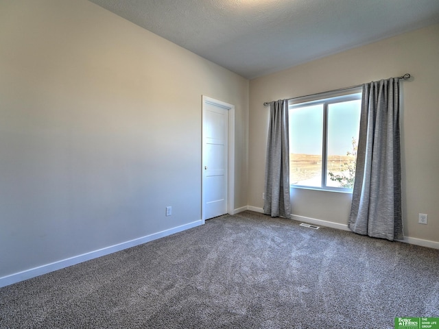 empty room with a textured ceiling and carpet