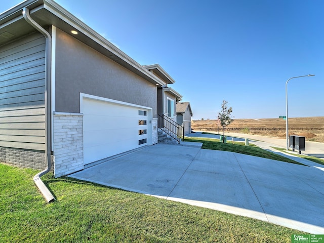 view of property exterior featuring a garage and a lawn