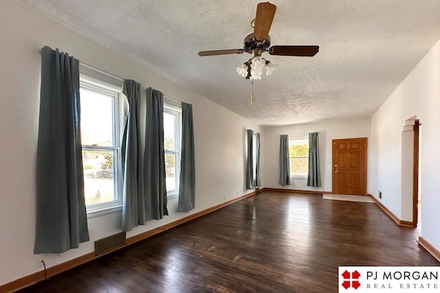 empty room with a textured ceiling, dark hardwood / wood-style floors, and ceiling fan