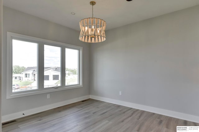 spare room featuring light hardwood / wood-style floors and a chandelier