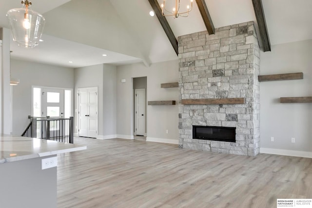 unfurnished living room featuring a fireplace, beam ceiling, light wood-type flooring, and high vaulted ceiling