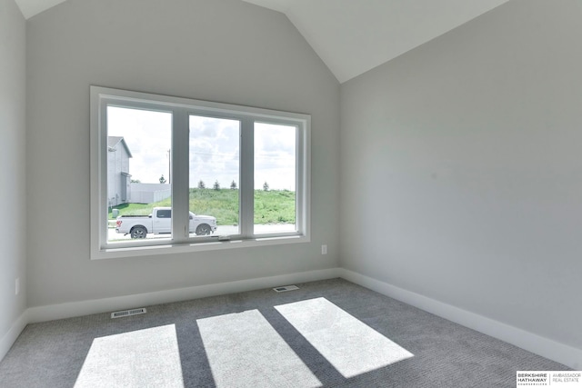 spare room featuring dark colored carpet and vaulted ceiling