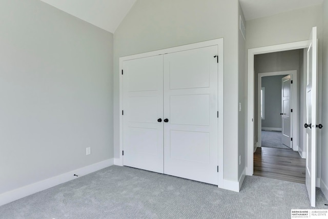 unfurnished bedroom featuring light carpet, vaulted ceiling, and a closet