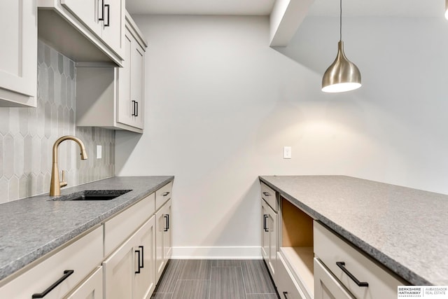 kitchen with white cabinets, sink, dark tile patterned floors, backsplash, and decorative light fixtures