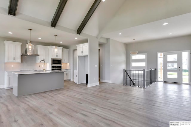 kitchen with appliances with stainless steel finishes, a kitchen island with sink, light hardwood / wood-style floors, and white cabinets