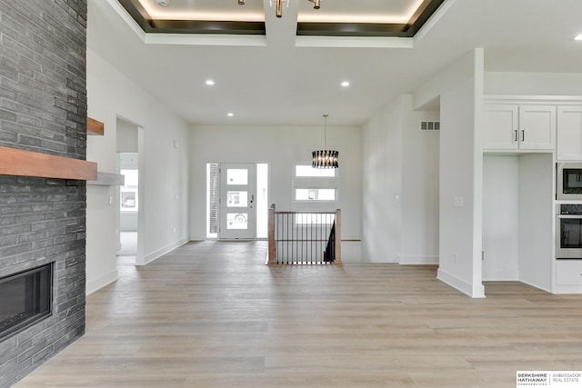 unfurnished living room featuring a brick fireplace and light wood-type flooring