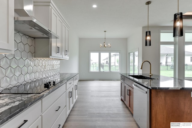 kitchen featuring stainless steel dishwasher, sink, wall chimney exhaust hood, and white cabinets