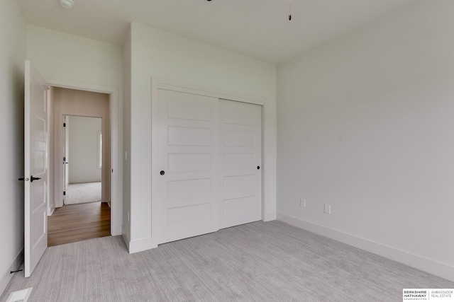 unfurnished bedroom featuring a closet and light colored carpet