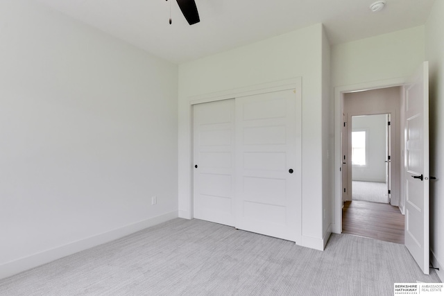 unfurnished bedroom featuring light colored carpet, ceiling fan, and a closet