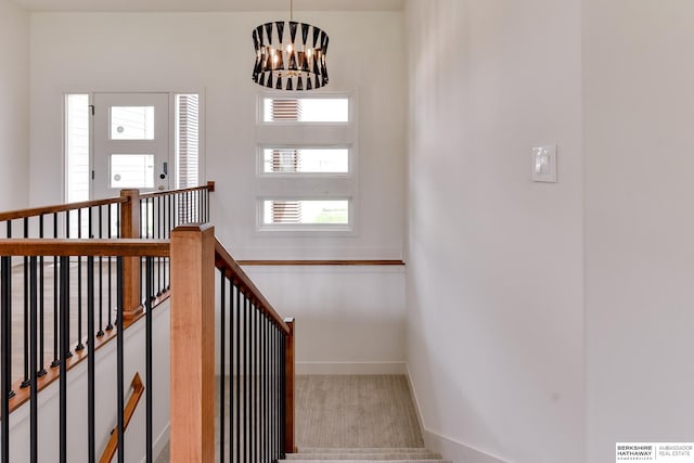 stairs with a chandelier and carpet flooring