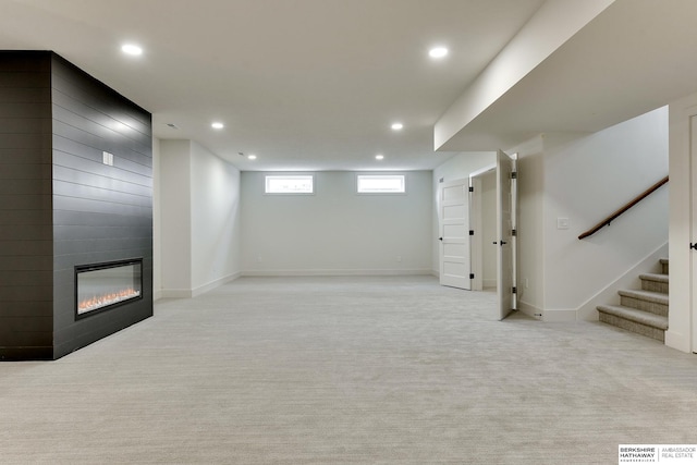 basement featuring a large fireplace and light carpet