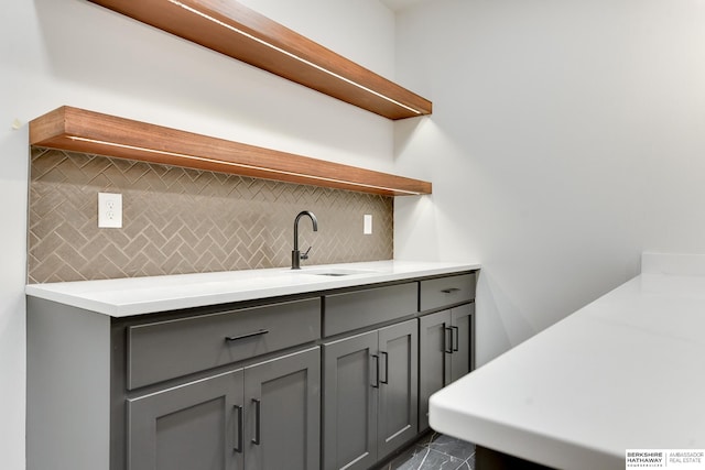 kitchen featuring gray cabinets, sink, and backsplash