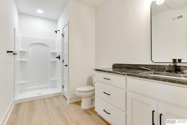 bathroom featuring toilet, a shower, vanity, and hardwood / wood-style floors